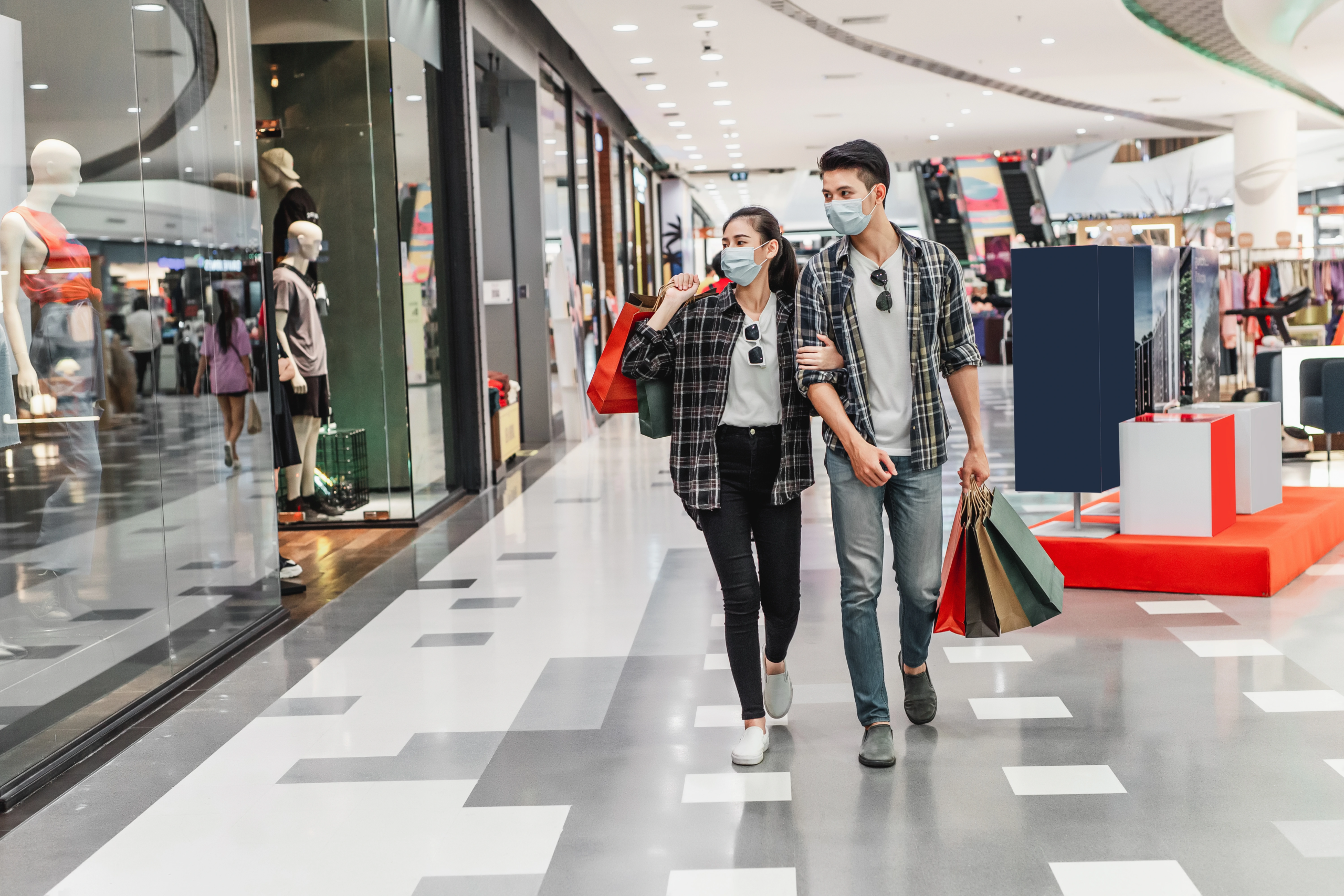 The Omaxe State young couple protection mask holding multiple paper shopping bag walking corridor large shopping mall scaled